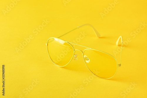 Yellow sunglasses on paper background, minimalism, monochrome.