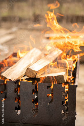 Flaming log (wood) in a metal outdoor brazier with ashes and smoke in rural courtyard photo