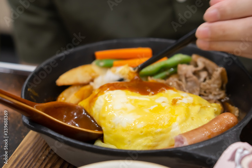 A man still eating Egg Lava Donburi Japanese food style omlet and fride pork with soy sauce in rice bowl.  photo