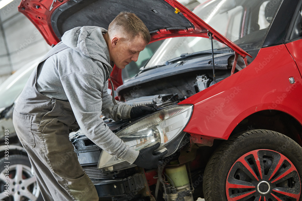 Auto service. Technician assembling an automobile headlight lamp. bodywork repair for insurance Auto service. Technician assembling an automobile headlight lamp. bodywork repair for insurance