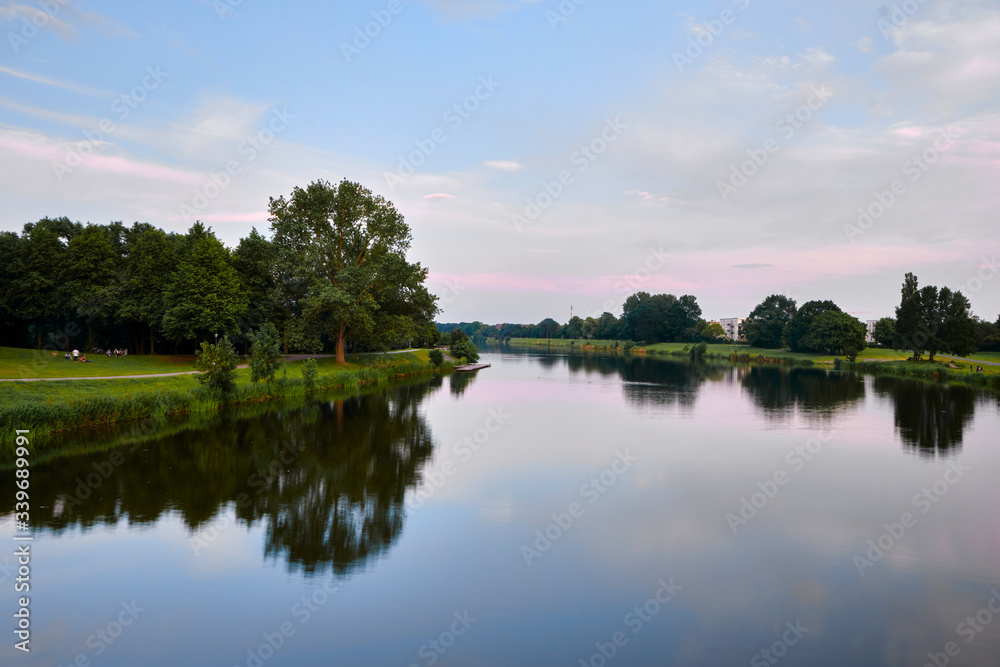 Water reflections of a serene river scene with a colourful sky in summer Water reflections of a serene river scene with a colourful sky in summer