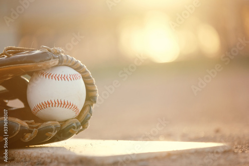 Photography Baseball in glove on ball field in park at sunset, blurred background with copy space beside sports equipment