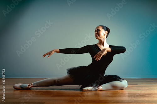 Adult beautiful woman 45-55 years old, ballerina in pointe shoes sits on the floor and poses for the camera. Active old age, the knowledge of life. Age-old ballet trainer.