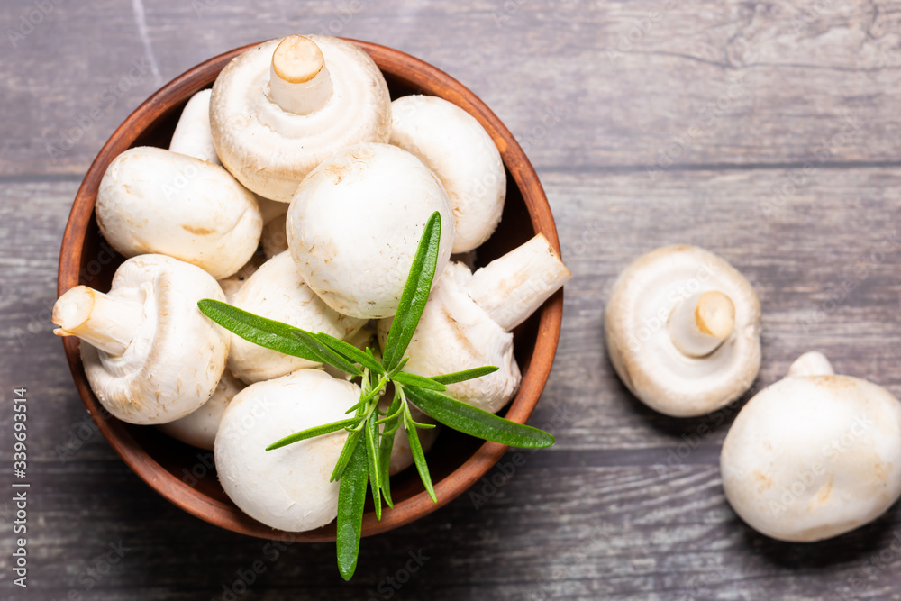 Fresh raw champignons in a clay bowl on wooden rustic background top view. Healthy diet food concept. Fresh raw champignons in a clay bowl on wooden rustic background top view. Healthy diet food concept.