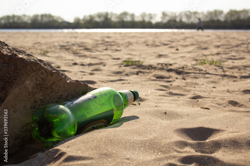 white plastic bottle lying on the beach and polluting the river and river life, the concept of fighting water pollution with plastic