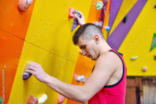 Young Man Climbing Up On Practice Wall