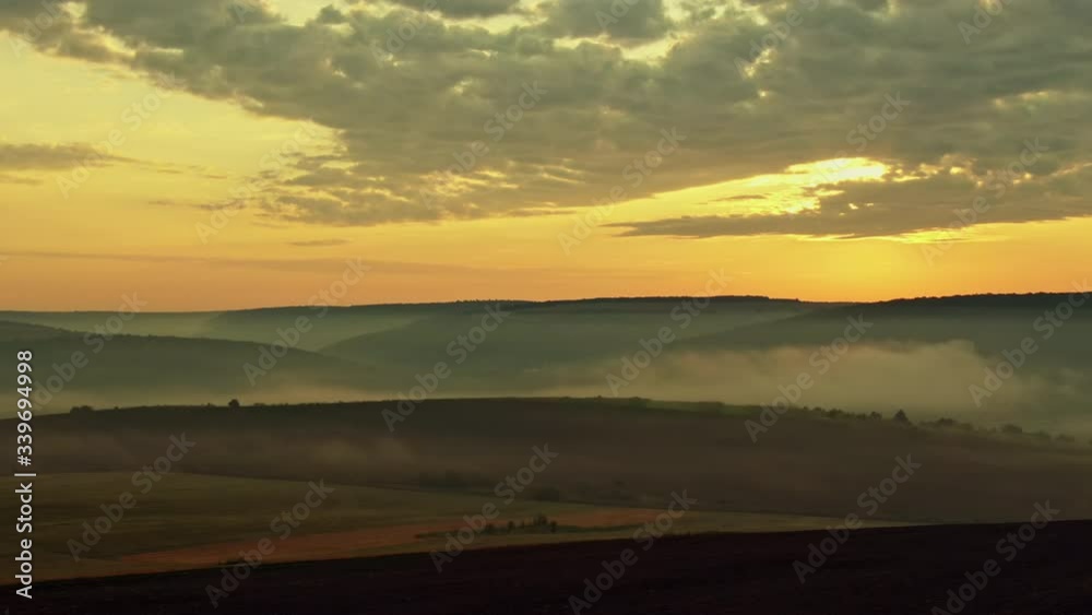 Misty autumn morning landscape at sunset with fogs, cloudy sky and hills - aerial view. Misty autumn morning landscape at sunset with fogs, cloudy sky and hills - aerial view.