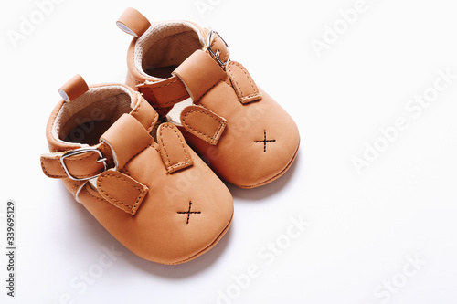 Pair of brown leather kids shoes on white background.