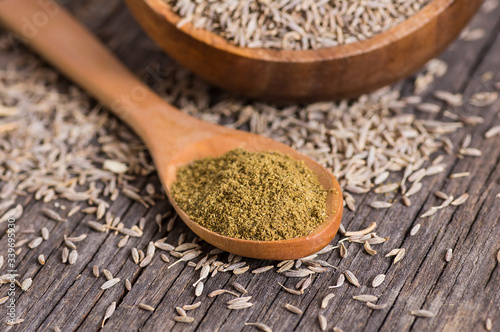 Fototapeta Naklejka Na Ścianę i Meble -  Pile of dry caraway spice with ground caraway powder in wooden spoon. Healthy food cumin spice concept ( Cuminum cyminum )