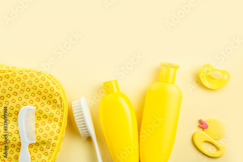 Spa and bath concept. Baby bath set. Rubber duck  washcloth  soap bottle  shampoo  towel and comb on yellow background.