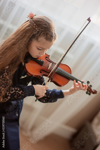 Home lesson for a girl playing the violin. The idea of activities for children during quarantine. Music concept