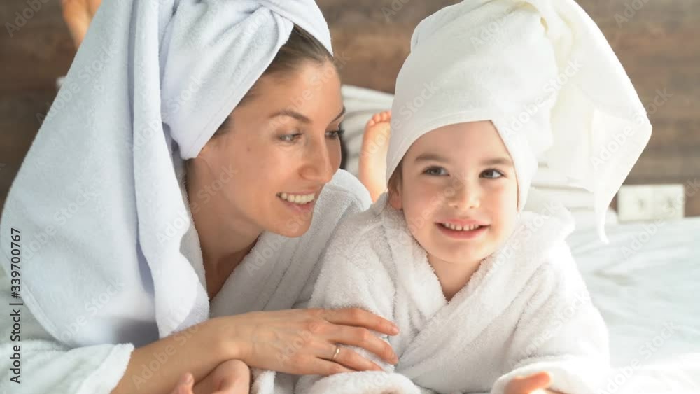 Portrait of a mother and little daughter on the bed with a remote control in their hands, switching channels, self-isolation at home in quarantine. Portrait of a mother and little daughter on the bed with a remote control in their hands, switching channels, self-isolation at home in quarantine.