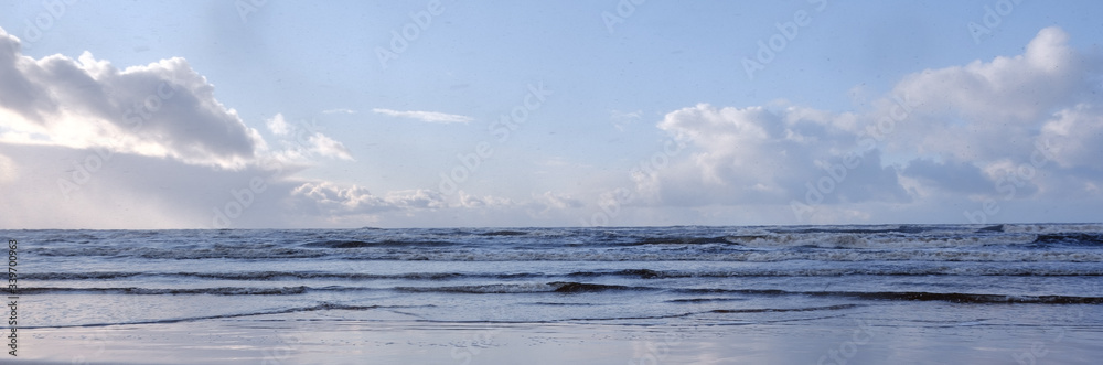 The Baltic Sea coast in winter, the sun shines brightly and there are clouds in the sky, but there are waves in the sea