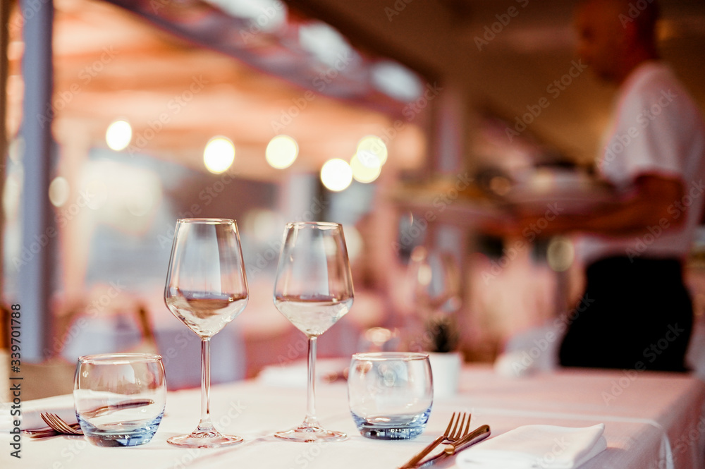 A glass of white wine on a table in a restaurant. Toned photo. Glare and light spots. Free space for text