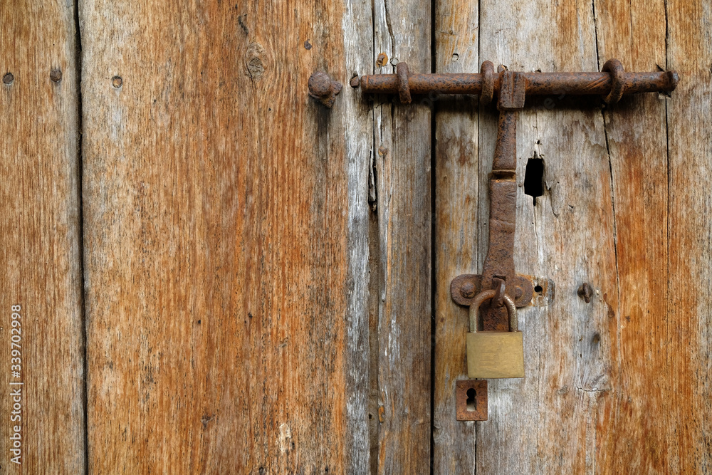 Weathered timber door closed with a latch and a padlock. Weathered timber door closed with a latch and a padlock.