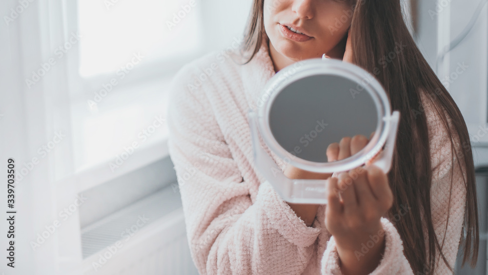 Woman relaxes after bath procedures and cares for face skin in his room. Morning skin care routine. Stay at home while quarantined to avoid coronavirus. Woman relaxes after bath procedures and cares for face skin in his room. Morning skin care routine. Stay at home while quarantined to avoid coronavirus.