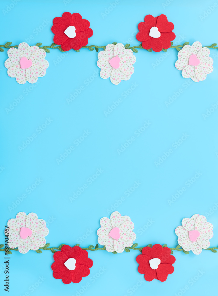 The flowers made of felt hearts with green leaves on blue background. Mother’s day, Valentine’s day, Wedding, Birthday or other suitable event celebration card concept. Flat lay with copy.