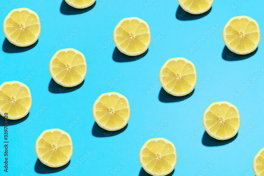 Lemon pattern on bright light blue background. Minimal flat lay food texture. Summer abstract trendy fresh concept.