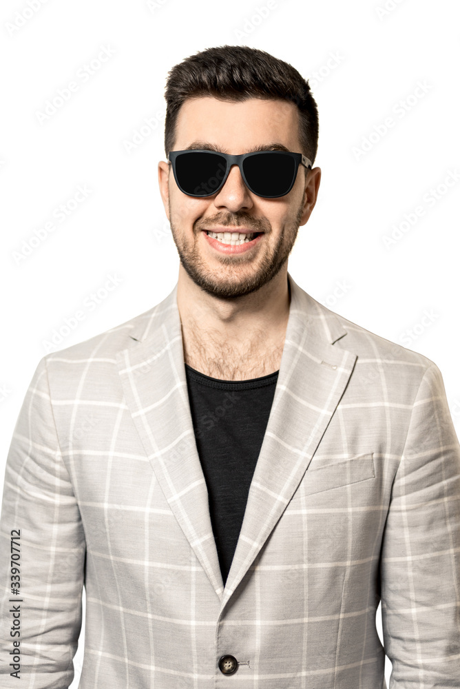 A young man with a beard in sunglasses and a white jacket on a white background. vertical frame A young man with a beard in sunglasses and a white jacket on a white background. vertical frame