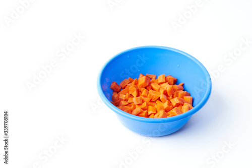 Sliced raw carrot in a plastic bowl isolated on a white background.