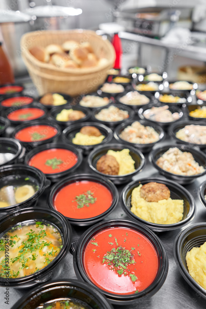 Food delivery. Different in plastic disposable lunch box with healthy natural food. Chicken broth, mashed soup, mashed potatoes with cutlet, seafood pasta, salads, pilaf with a fresh bun.