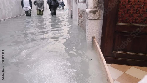 High level of water on the alleys during the flood in Venice, people walking through the flooded alley. 4k photo