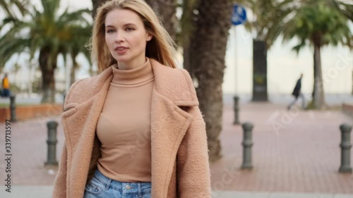 Tracking shot of attractive stylish blond girl confidently crossing road at cozy street