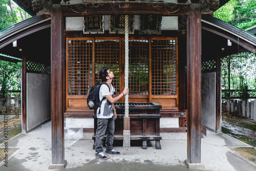Traveler ringing the bell in wooden altar at shinto shrine in Osaka, Japan   © Samuel Ponce