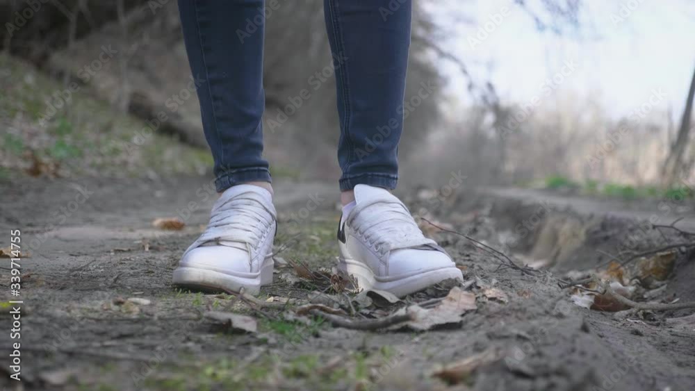 Focus on white sneakers. Active healthy woman hiking in autumn forest. Recreation and healthy lifestyle outdoors in nature. Focus on white sneakers. Active healthy woman hiking in autumn forest. Recreation and healthy lifestyle outdoors in nature.