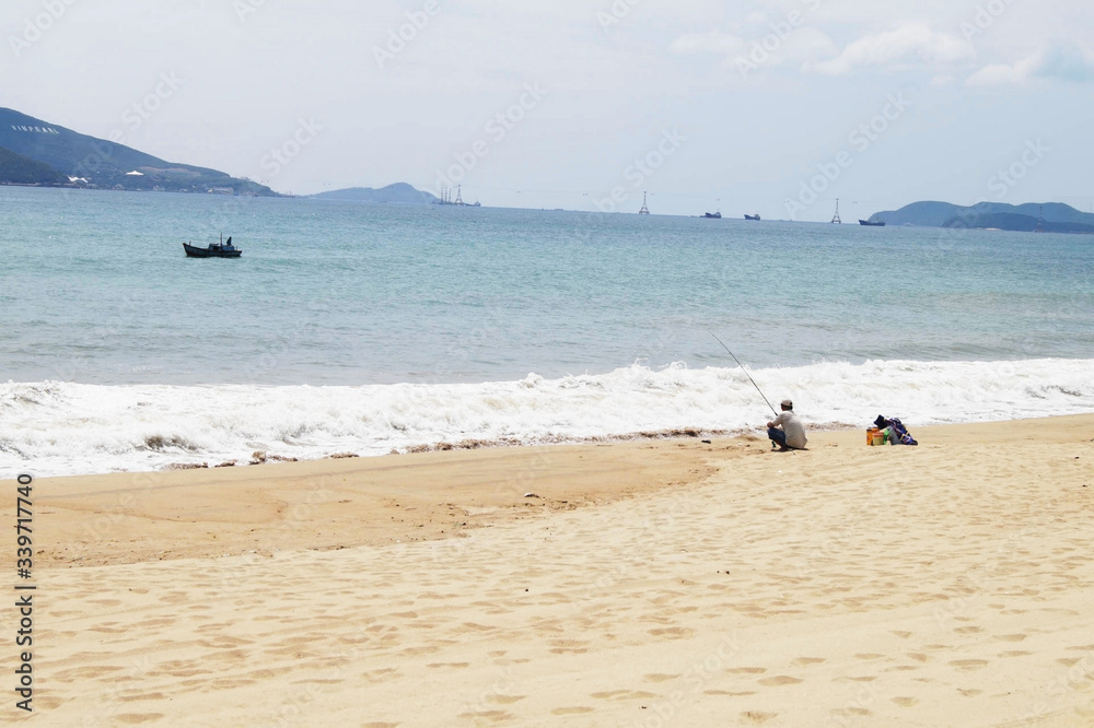 Fisherman on sandy shore of an Asian warm beach by the sea