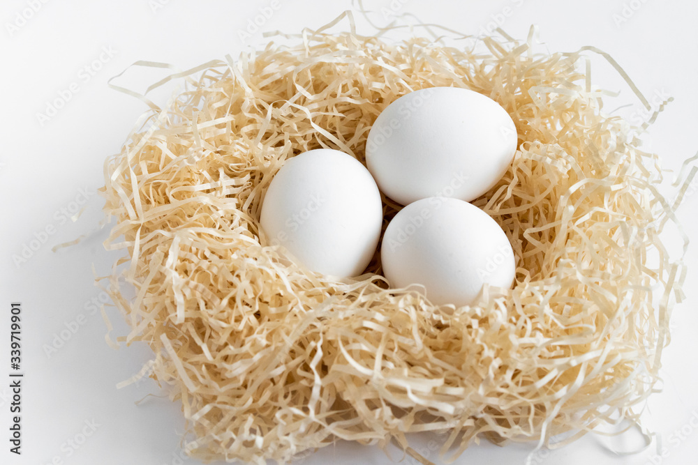 white chicken eggs in a nest on a white background, Easter eggs, place for text