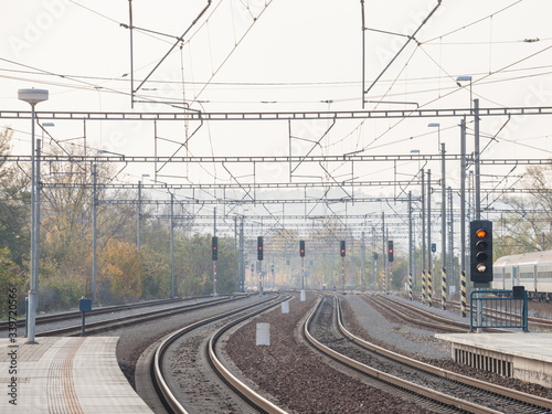 Recently reconstructed tracks on the modernized platforms of a suburban train station in a capital city of Central Europe, with brand new concrete structures signalling in the background.