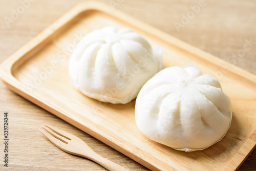 Steamed buns stuffed with minced pork on wooden plate with fork ready to eating, Asian food
