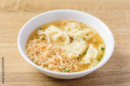 Instant noodles soup and wonton dumpling stuffed with minced pork in a bowl on wooden background, Asian food