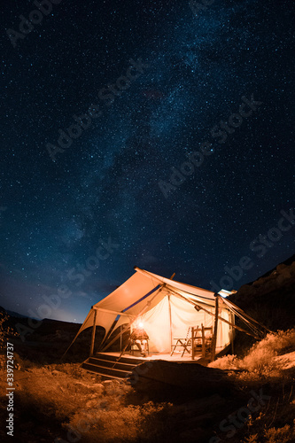 A canvased tent in the desert with the Milky Way at night