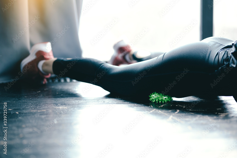 Close-up inflated legs in leggings. The girl leans a hip on the green Ball Myofascial. Massage of the thighs. Close-up inflated legs in leggings. The girl leans a hip on the green Ball Myofascial. Massage of the thighs.