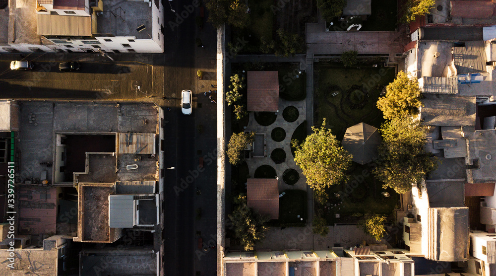 Aerial view on part of the historic center in Arequipa, Peru with its unique Spaniard architecture during the sunset. Top-down view on the patio with garden, a street, car passing and other buildings.