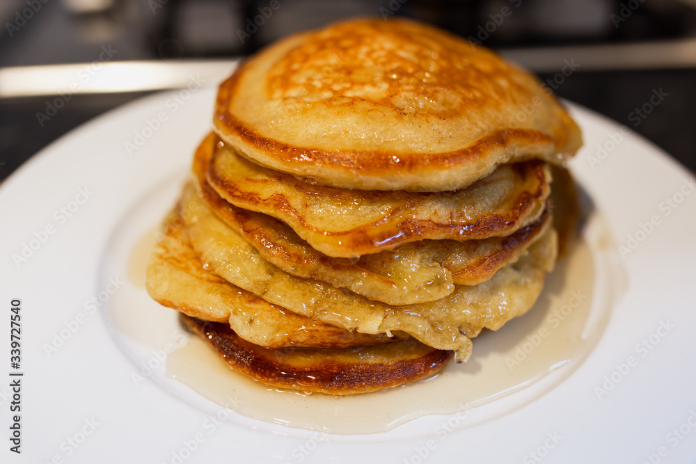 Fresh homemade classic pancakes with maple syrup in a white plate on a wooden board. Fresh homemade classic pancakes with maple syrup in a white plate on a wooden board.