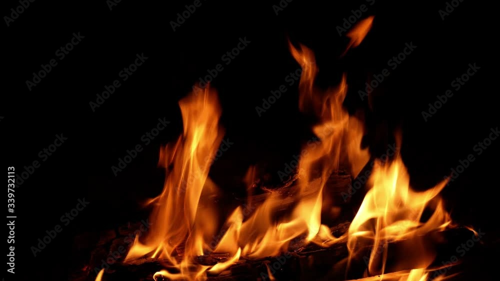 Hot fire and flickering flames from wood logs burning in a fireplace, with dark background and copy space on left, in a relaxing closup clip in a loop. Relaxation concept. Hot fire and flickering flames from wood logs burning in a fireplace, with dark background and copy space on left, in a relaxing closup clip in a loop. Relaxation concept.