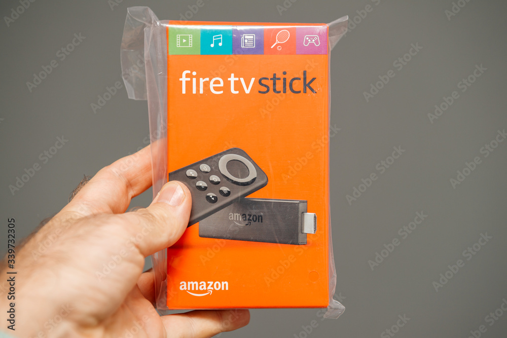 Paris, France - Jul 15, 2019: man hand holding new plastic wrapped new Amazon  Fire TV Stick with Alexa Remote a digital media player and its microconsole  remote developed by Amazon Stock