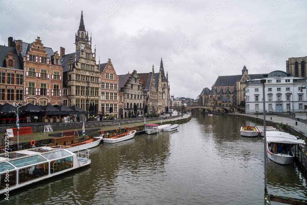 View of Sint-Michielsbrug, Stone arch bridge in the city center and architecture traditional houses along Lys (Leie) river (canal) in Gent. Beautiful postcards in the city.