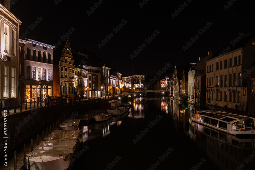 Calm water canal and old medieval buildings at night, Ghent, Belgium