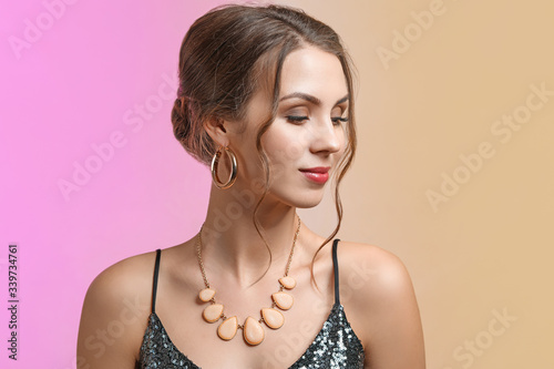 Young woman with beautiful jewellery on color background