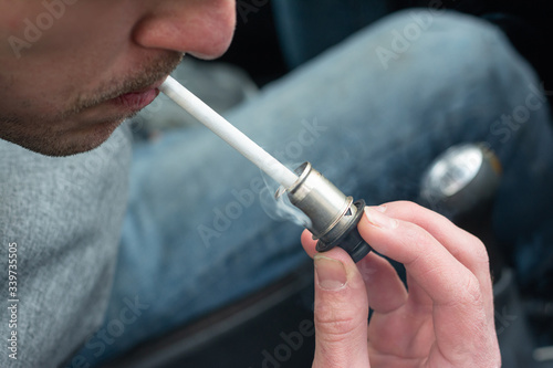 a man lights a cigarette with an electronic cigarette lighter in a car. bad habits. inside the car