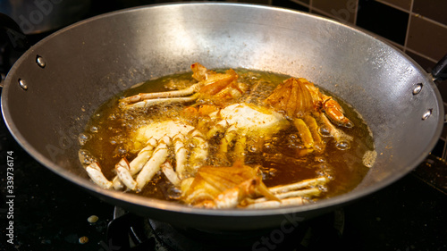 Close up view of crab being deep fried in a hot boiling oil in metal wok.