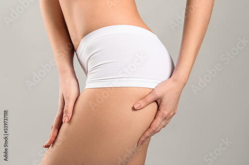 Young woman in underwear on grey background. Plastic surgery concept © Pixel-Shot