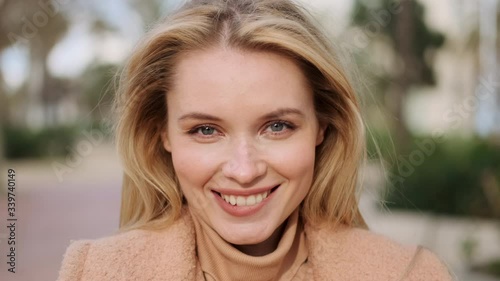 Portrait of flirty blond girl happily looking in camera on street