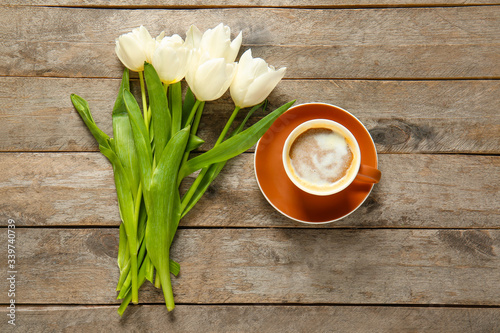 Cup of coffee and flowers on wooden background