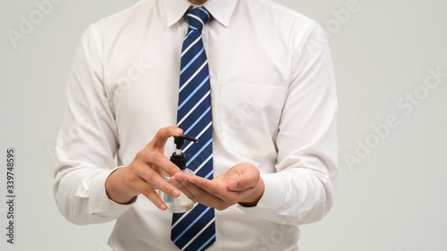 Coronavirus Hygiene concept. Business man working in office wearing protective mask cleaning hands with sanitizer gel. Prevent the spread of germs and bacteria and avoid infections corona virus. photo