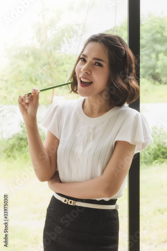 Portrait of beautiful young woman working with documents at office while talking on phone in the office.